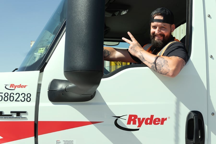 Ryder driver in cab of fleet truck giving victory hand symbol for distribution services