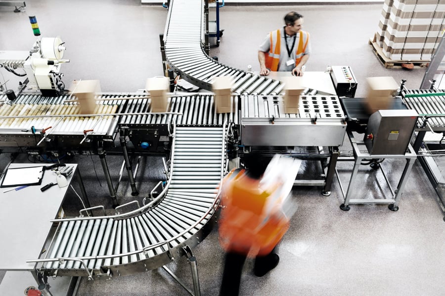 Packages on a conveyor belt in a warehouse with workers nearby