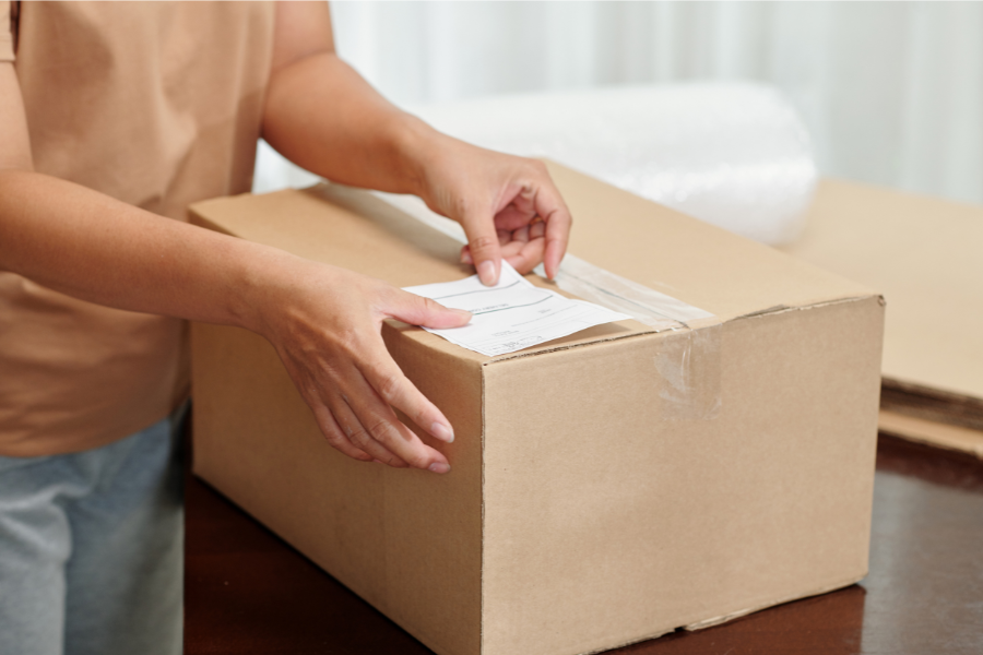 Turn Returns into Revenue Person putting a return label on a box
