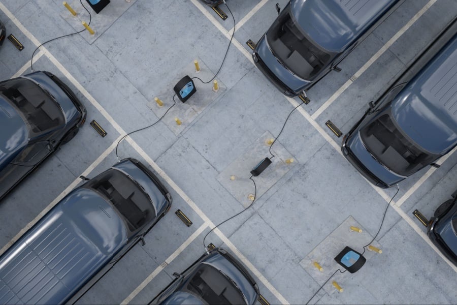 a fleet of commercial EV cargo vans on chargers