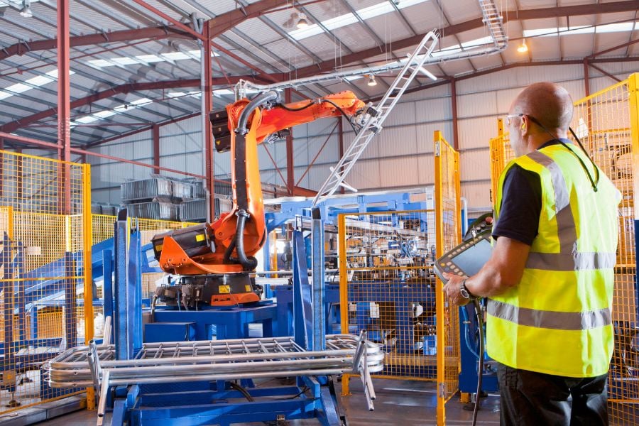2026 Supply Chain Trends You Should Be Anticipating Worker controlling robotic machinery lifting steel fencing, representing supply chain trends in manufacturing