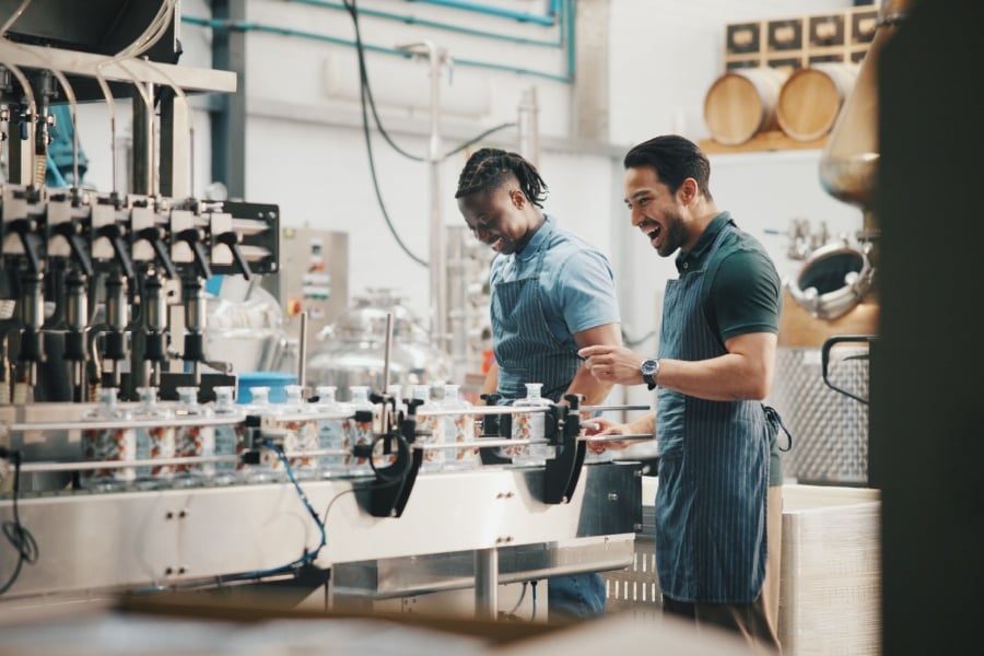 The State of the Beverage Industry Two male workers bottle beverages on a conveyor line.