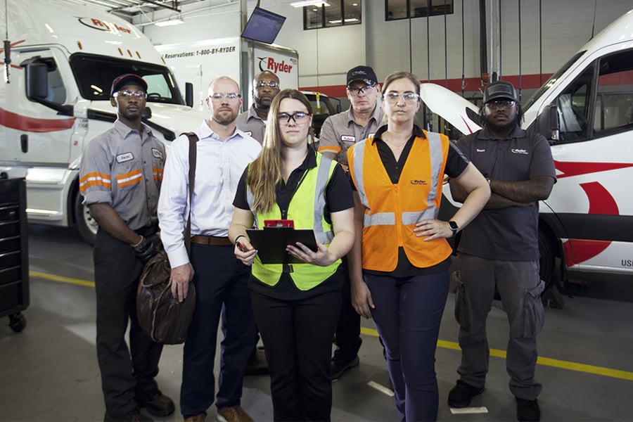 A group of Ryder technicians and staff gathered together in a maintenance shop A group of Ryder technicians and staff gathered together in a maintenance shop