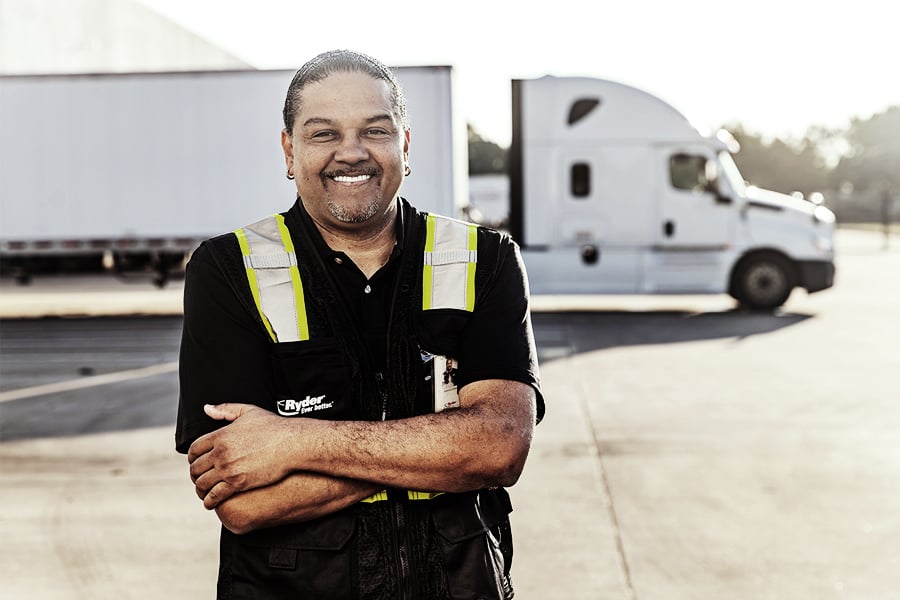 Ryder CDL truck driver standing with arms crossed in front of a semi truck Ryder CDL truck driver standing with arms crossed in front of a semi truck