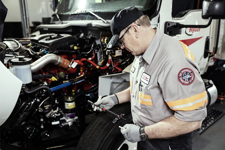 Ryder diesel technician performing maintenance under the hood of a semi truck Ryder diesel technician performing maintenance under the hood of a semi truck