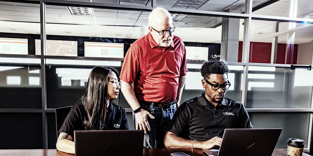 Three Ryder logistics professionals reviewing carrier data together Three Ryder logistics professionals reviewing carrier data together