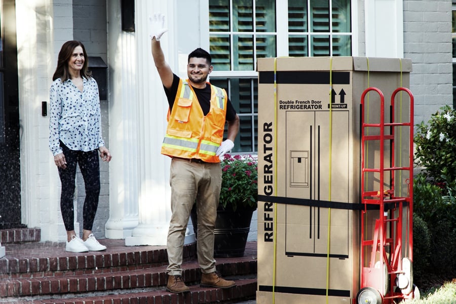 White glove delivery technician unloading a boxed refrigerator at a customer’s home White glove delivery technician unloading a boxed refrigerator at a customer’s home