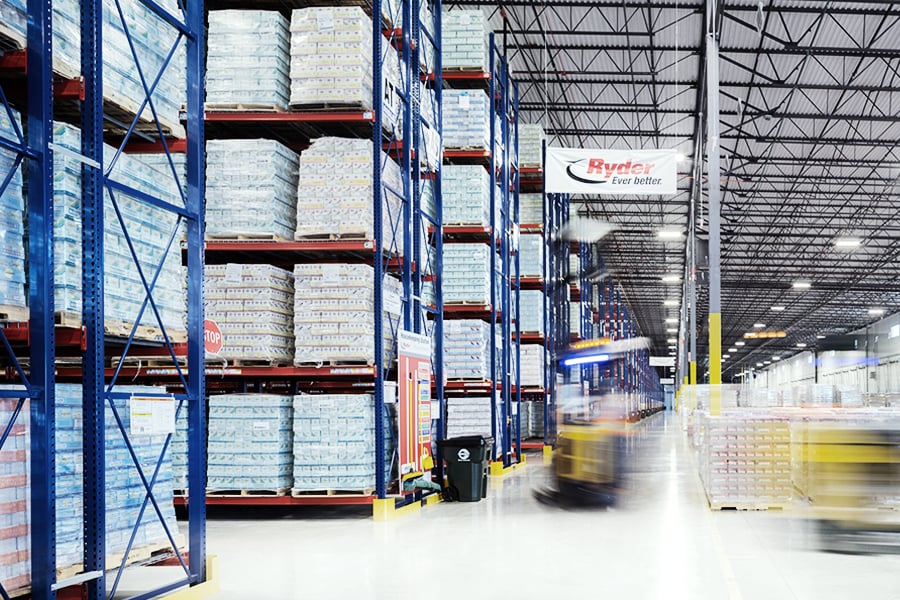 Forklift moving pallets through a large warehouse with high storage racks Forklift moving pallets through a large warehouse with high storage racks
