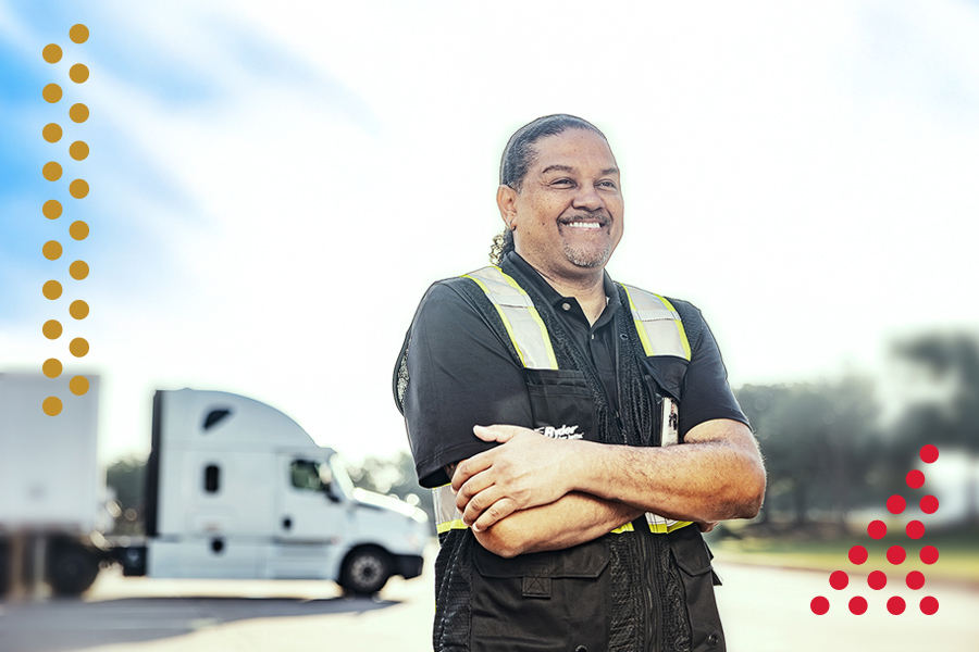 Truck driver standing with arms crossed in front of a semi-truck Truck driver standing with arms crossed in front of a semi-truck