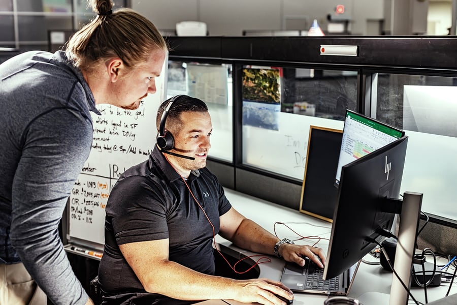 Logistics team members coordinating shipments at computer workstations in an office Logistics team members coordinating shipments at computer workstations in an office