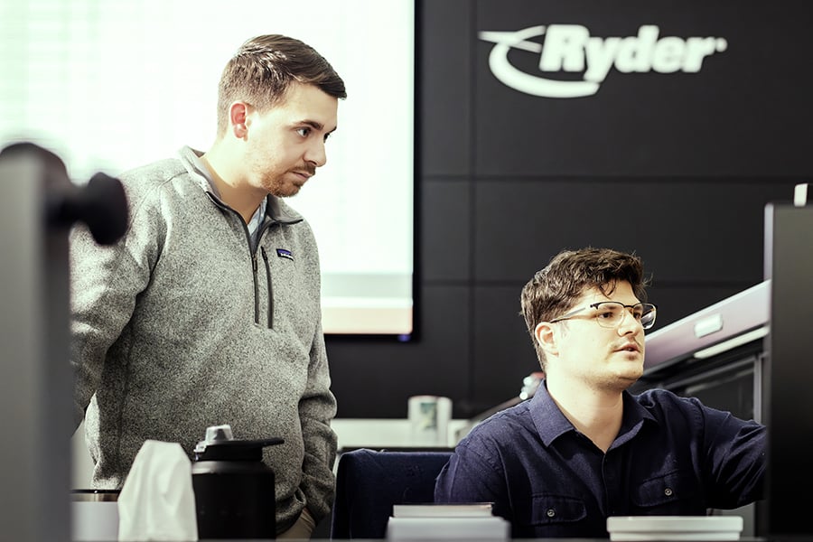 two Ryder transportation management employees working on a monitor two Ryder transportation management employees working on a monitor