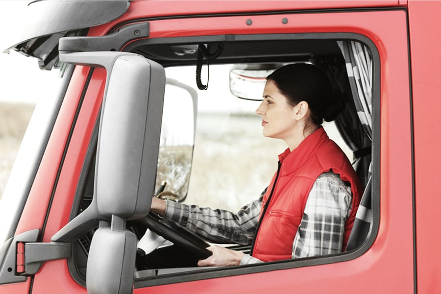female freight shipping driver in cab of truck